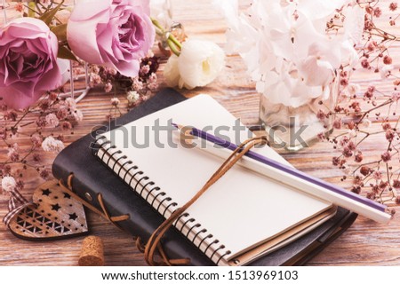 White ranunculus and hydrangea flowers in bottle with craft envelope on pink rustic wooden background