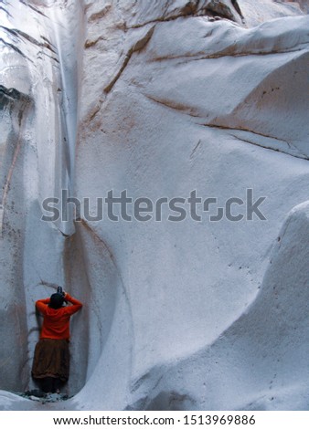 A woman photographing abstract patterns inside a slot canyon.