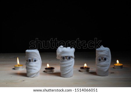 Halloween. DIY. Mummy creative idea from toilet tube recycle, and candle on table with black background.