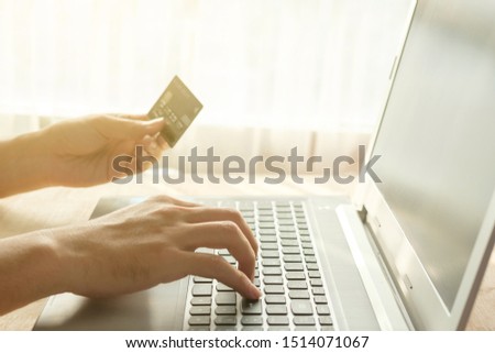 Hands of someone paying with credit card for buy something in internet on warm light.