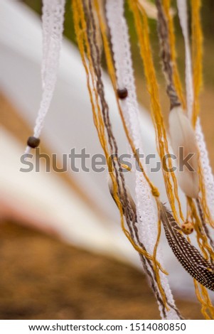 Close-up of a gray quail feather, lace, cord on a forest background. ribbons develop in the wind. Handmade still life. Shallow focus
