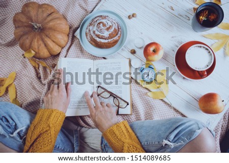 atmospheric autumn background. girl holds cup of coffee. bun, pumpkin, apples, book, headphones, retro camera in frame
