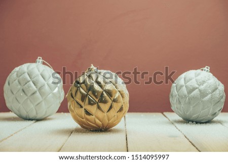 Beautiful Christmas baubles on a new wooden table fell by snow and dark red wall background behind.