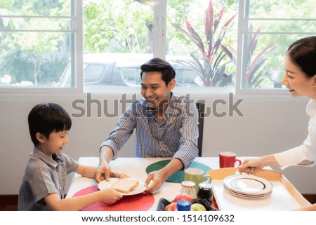 Asian family, father and son having breakfast together with mother in dining room, happy family concept