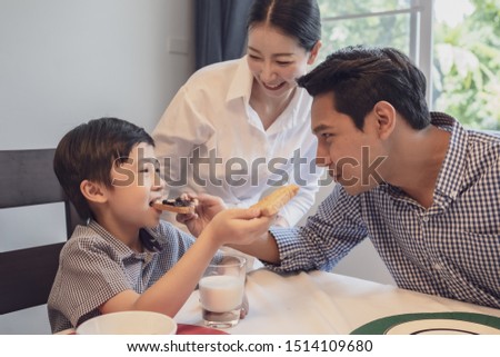 Asian family, father, mother and son having breakfast, bread with jam together in dining room, happy family concept