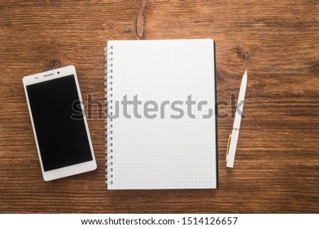 Notebooks, phone and pen on brown background