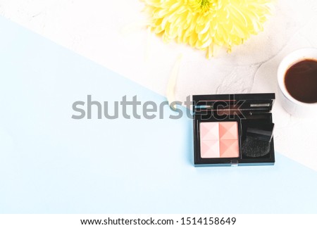 Moscow/Russia-CIRCA 09.2019: an image of blush makeup, a brush on a blue and white backdrop, cup of coffee golden daisy flower