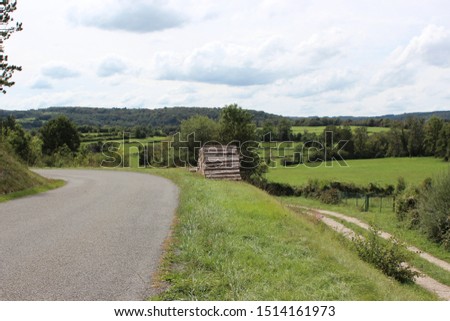 Rural landscape with trees and country road in France. Photo was taken on a beautiful sunny day with an awesome blue sky and clouds.