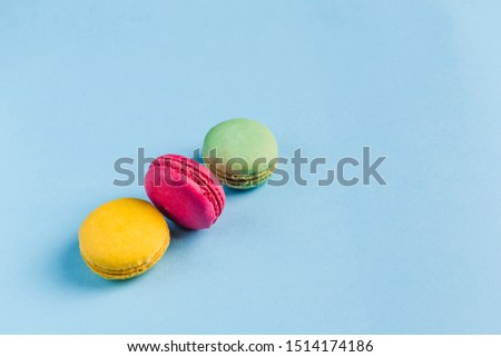 Multicolored macaroons on a blue background, top view, Flatley with copy space. Dessert with melon, lemon and raspberry flavor. Art