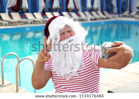 Authentic Santa Claus taking selfie near swimming pool outdoors