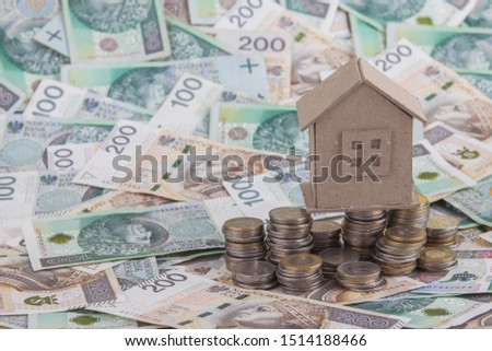 the cardboard model of the house lies on scattered Polish banknotes