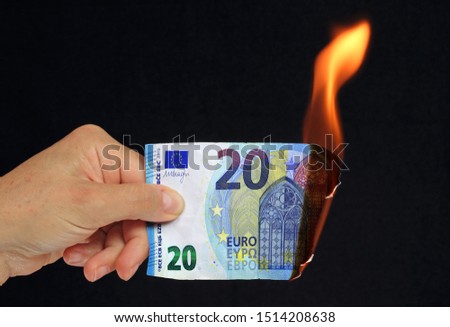 Hand holding a  20 euros bank note burning conceptual picture on black background