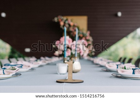Table number, figure of wooden material. Little stylish and thin candles in the candlesticks on the festive wedding table. Elegant wedding decor