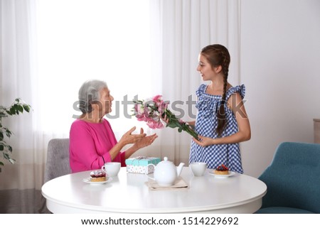Preteen girl congratulating her granny at home. Happy Mother's Day