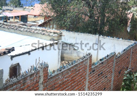 A house in the favelas or poor neighboorhood with fencing brick walls topped with broken glass