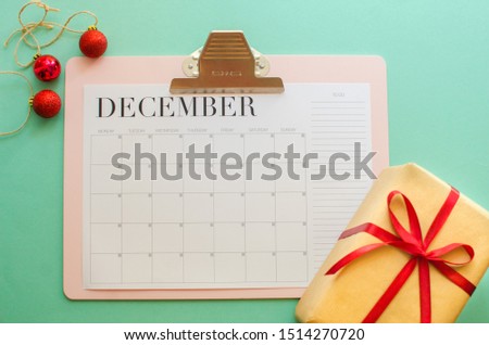 year end review, date planning, appointment, deadline or holiday concept on blue background next to black clean calendar on month of December.