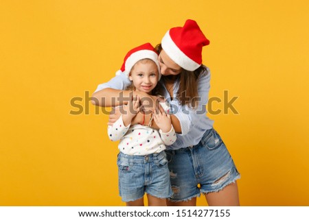 Woman child baby girl 4-5 years old in Christmas Santa hat. Mommy little kid daughter isolated on yellow background studio portrait. Happy New Year celebration holiday concept. Mock up copy space