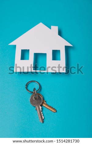 Silver key with house figure on blue background. Top view.