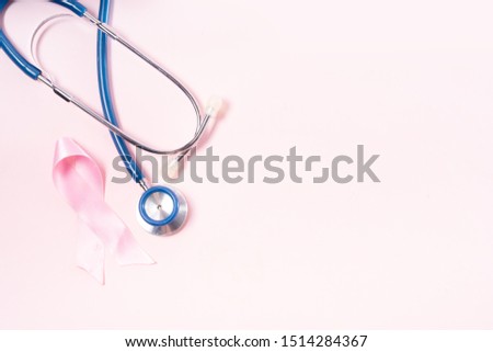 Pink ribbon, symbol of breast cancer awareness with stethoscope, copy space on pink background