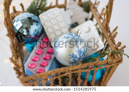 pharmacy theme. pink and white pills in a basket with christmas balls in blue on a white background with lights
