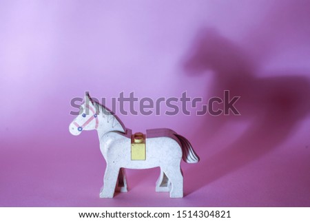 WHITE TOY HORSE AND THIS PICTURE HAS A PINK BACKGROUND