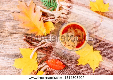 Fall yellow leaves with cup of coffee on woolen plaid autumn background, retro toned