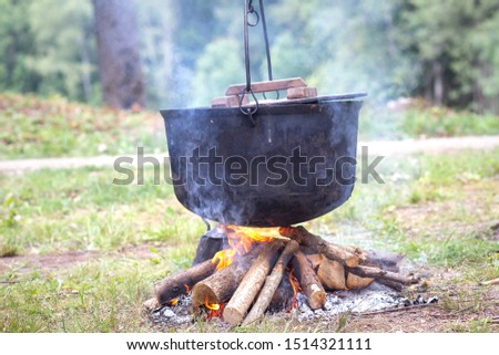 A hiking pot outside on a campfire