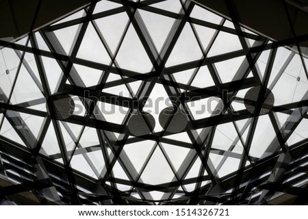 Collage photo of transparent ceiling with metal framework and round lighting fixtures in an office building. Abstract black and white modern architecture background with geometric pattern.