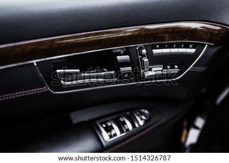 opening handle and control mechanisms on the door trim of a business class car with shallow depth of field