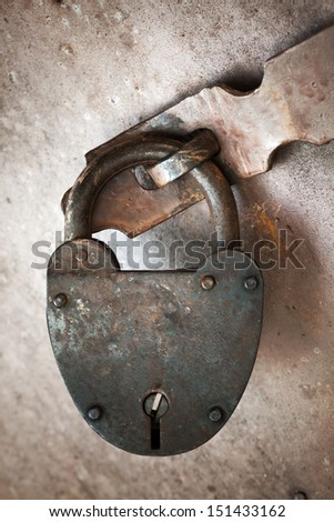 Old rusted lock hangs on metal door. Close-up photo