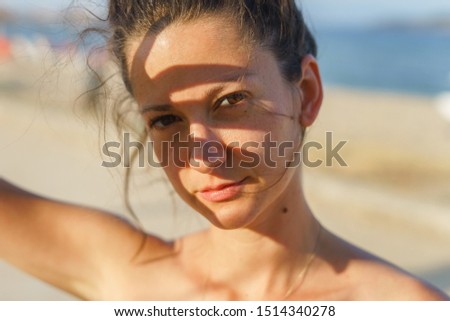 Portrait of young woman in sunny day summer or spring or autumn with shade on her face brunette real person looking to the camera