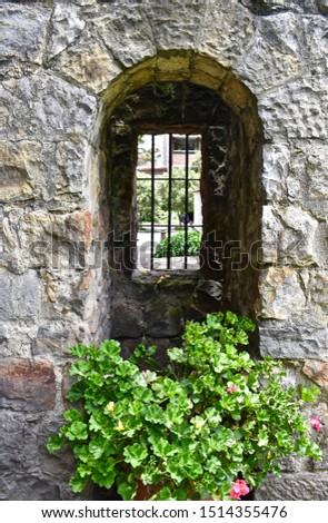 Colonial style window built with large rocks and surrounded by flowers.