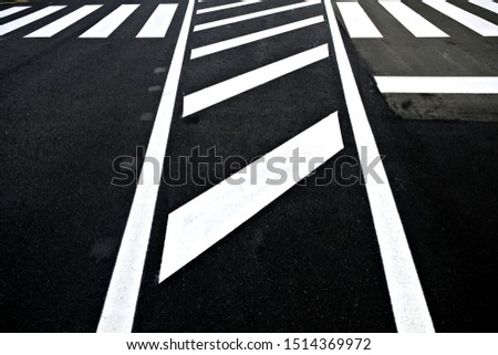 Abstract perspective section of white reflective paint road signage on black asphalt road.