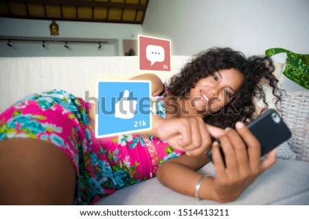 internet social media app likes and chat comments icons composite on young beautiful and happy mixed ethnicity latin African American woman at home couch using mobile phone as influencer