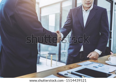 Two confident business man shaking hands in meeting room, hipster vintage picture style.