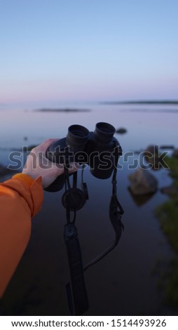 Hand with binoculars on a marine background, looking through the concept of binoculars, travel, find and search