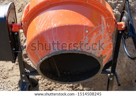 Picture of an orange concrete mixer ready to making concrete  in a construction site