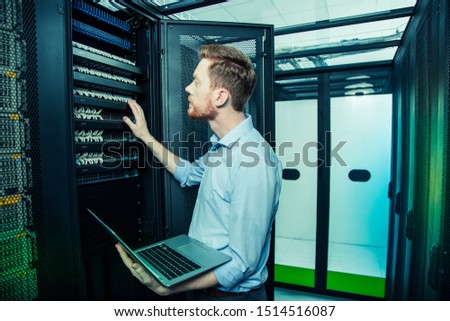 Everyday work. Smart handsome man holding his new laptop while working in the data center Royalty-Free Stock Photo #1514516087