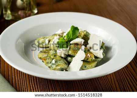Green Gnocchi with basil, spinach, pesto feta cheese in composition with green cloth and olive oil. Close up, selective focus. Traditional italian cuisine.