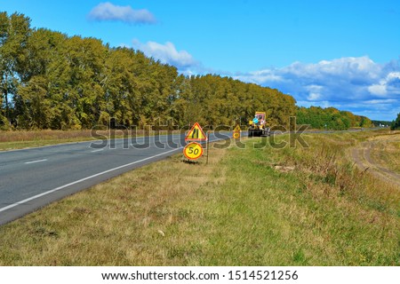 road signs-narrowing of the road, speed limit and repair work outside the city and road machinery away