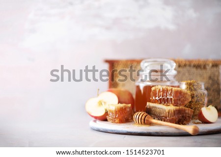 Apples with honey jar, honeycomb on grey background with copy space. Rosh hashanah jewish new year holiday celebration.