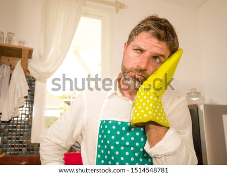 funny lifestyle portrait of mid adult unhappy and stressed man in kitchen apron feeling frustrated and upset overwhelmed by domestic chores washing dishes tired suffering stress 
