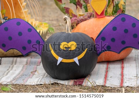 Scary smiling halloween black pumpkin, outdoors, close up. Halloween holiday concept with black pumpkin decor
