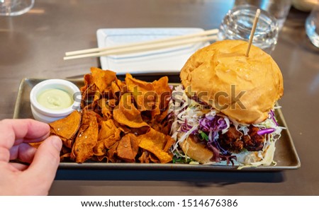 A Japanese restaurant meal of chicken and coleslaw burger with sweet potato fries and wasabi mayonnaise