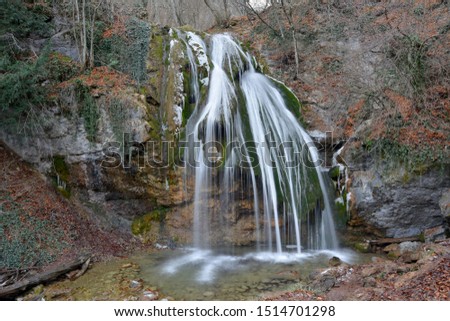Djur-Djur waterfall (Crimea Mountains) in winter beginning. Snow inclusions and icicles,  fallen leaves are seen on photo.