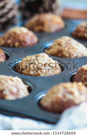 Fresh from the oven, homemade pumpkin muffins with streusel. Selective focus on center muffin with extreme blurred foreground and background.
