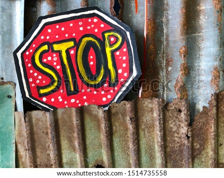 Stop sign on rusted corrugated iron panel.