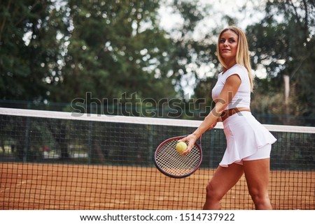 Ready for the game. Female tennis player in sportive clothes on the cort at summer daytime.