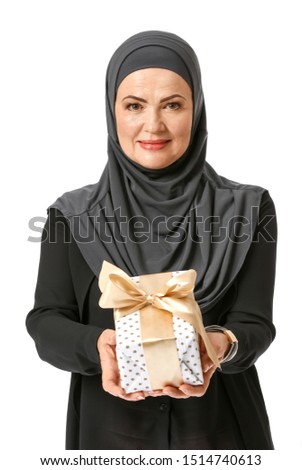 Beautiful mature Muslim woman with gift box on white background