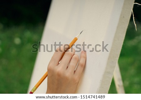 white canvas in hand pencil draws a picture